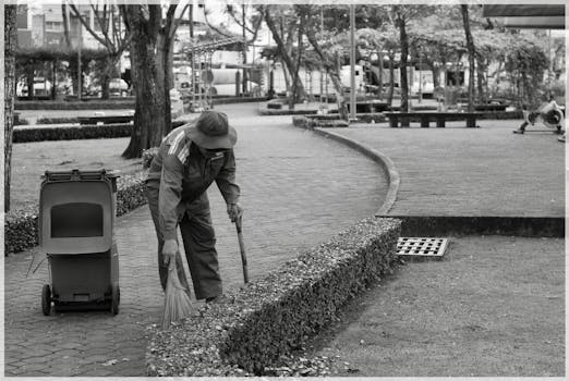 Sanitation worker sweeping in a park, highlighting urban cleanliness efforts.